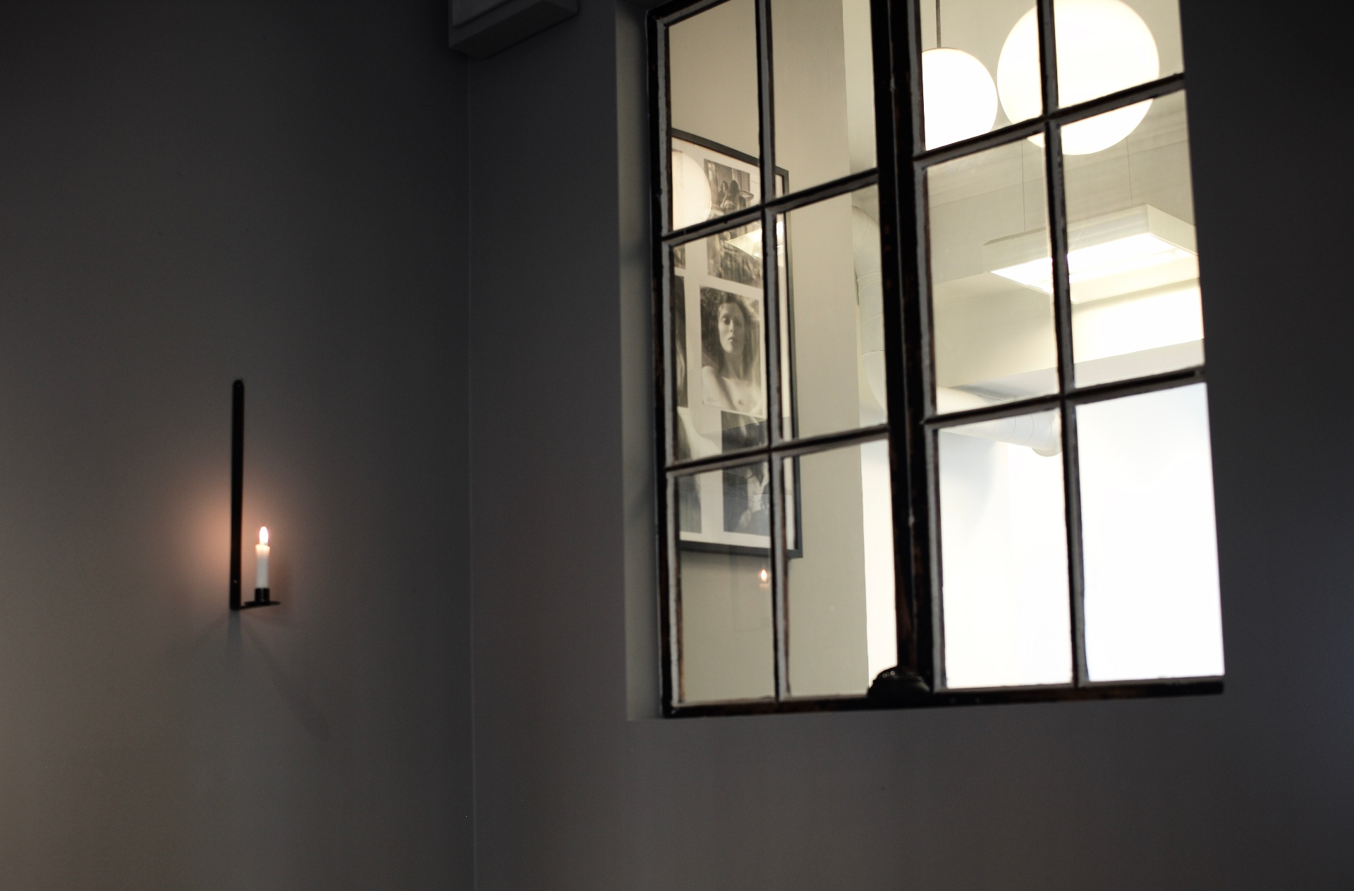 Candle and black-framed interior window at Atelier 27